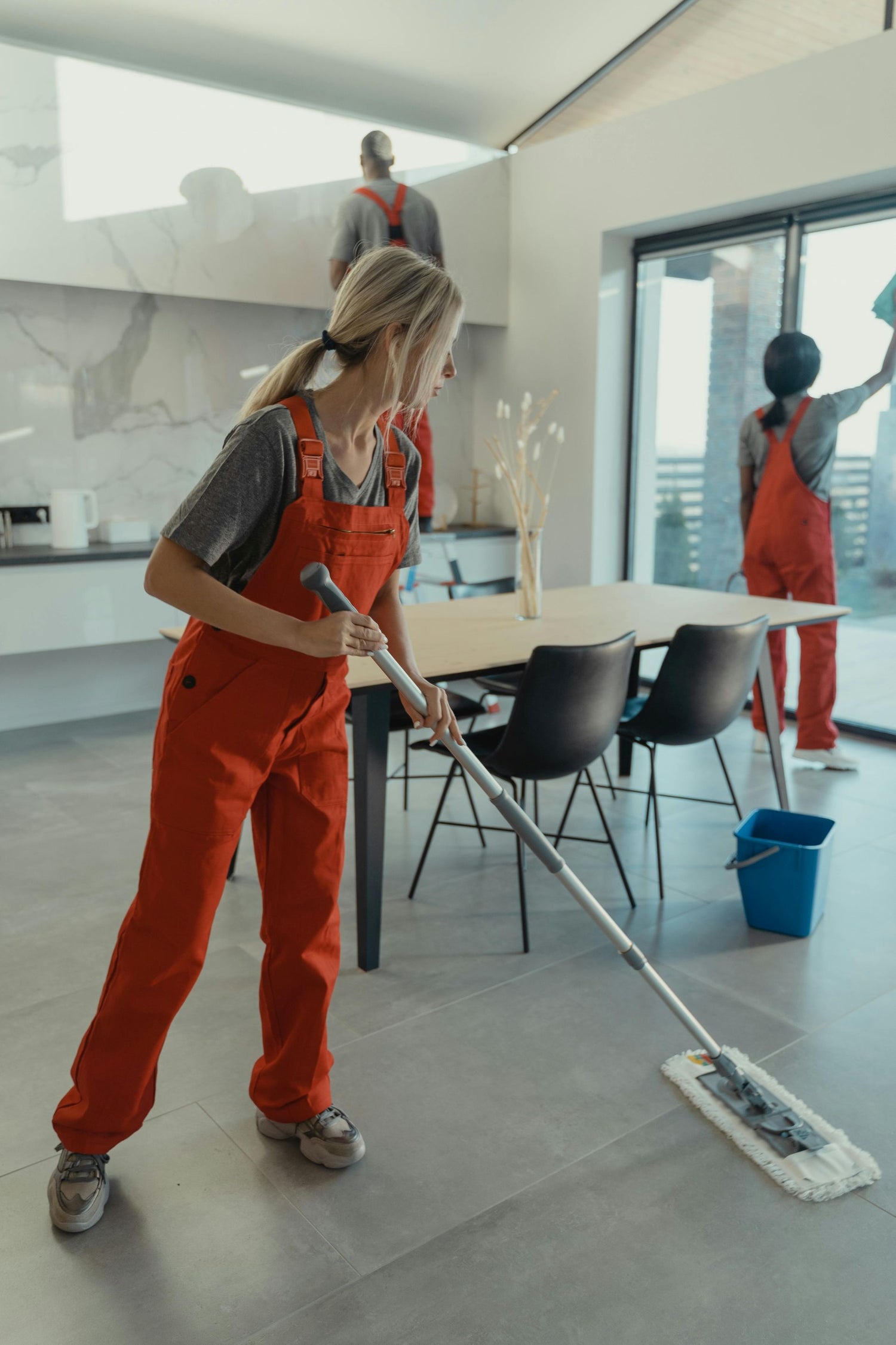Person cleaning a modern office space with others in the background.